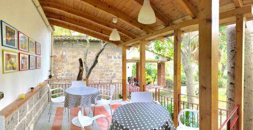 un patio con 2 mesas y sillas en un porche en La Gallina Felice B&B, en Meta