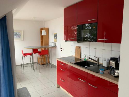 a kitchen with red cabinets and a sink and a table at Ferienwohnung Seeblick, Ferienanlage "Blaumuschel" in Lubmin