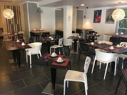 a dining room with tables and white chairs at Lagrange Aparthotel Montpellier Millénaire in Montpellier