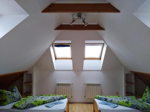 a attic bedroom with two beds and two windows at Penzion Soltis in Liptovské Revúce