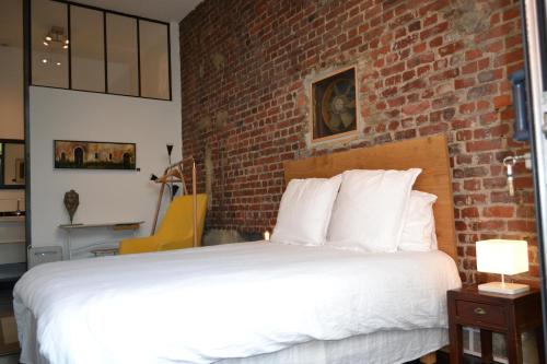 Cama en habitación con pared de ladrillo en Chambre d'hôtes la Teinturerie en Roubaix