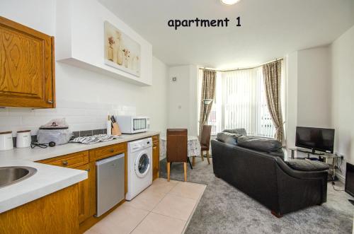 a kitchen and living room with a couch and a table at Welsh Cosy Apartments in Llandudno