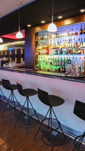 a bar with chairs and bottles of alcohol at Radisson Blu Hotel Toulouse Airport in Blagnac