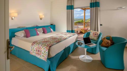 a bedroom with a bed and a table with a laptop at El Faro Hotel & Spa in Porto Conte