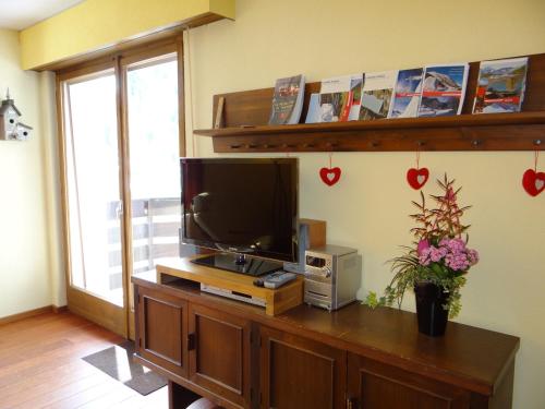 una sala de estar con TV en un centro de entretenimiento de madera en Arolles 303, en Arolla