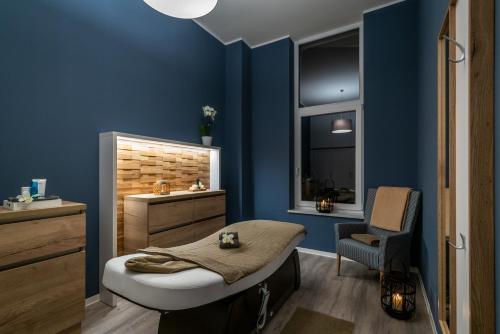a bathroom with blue walls and a bed and a chair at Müritzpalais in Waren