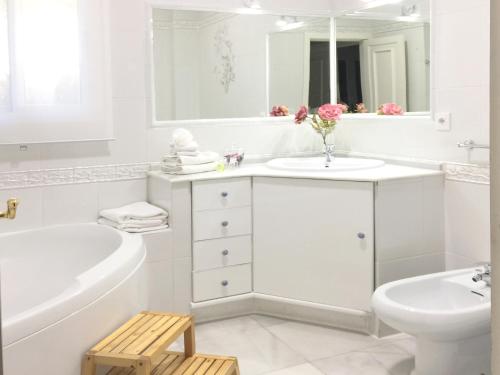 a white bathroom with a tub and a sink and a toilet at Villa de Lujo con Jardines y Piscina in El Puerto de Santa María