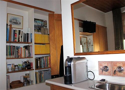 a kitchen with a sink and a mirror and books at Borough B&B in Eaglehawk