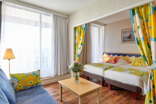 une chambre d'hôtel avec deux lits et un canapé dans l'établissement Résidence Vacances Bleues Le Grand Large, à Biarritz