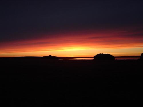 a sunset over the ocean with rocks in the foreground at Kidagil Guesthouse in Thingeyjarsveit