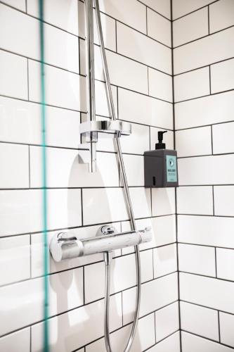 a shower in a bathroom with white tiles at Comfort Hotel Kista in Stockholm