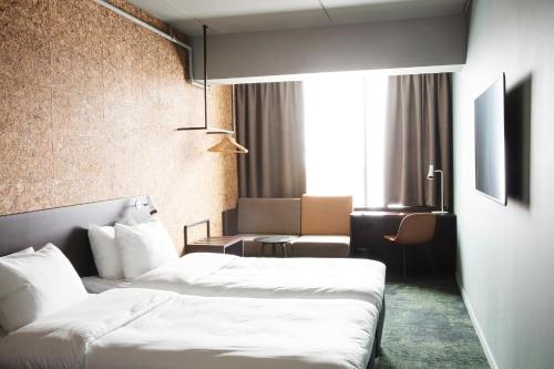 a hotel room with two beds and a chair at Comfort Hotel Kista in Stockholm