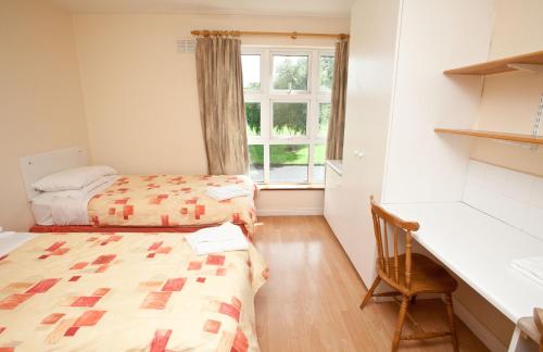 een kamer met 2 bedden, een bureau en een raam bij Courtbrack Accommodation - Off Campus Accommodation in Limerick