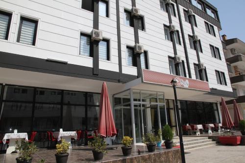 a building with tables and umbrellas in front of it at ECS Suw Hotel in Atakum
