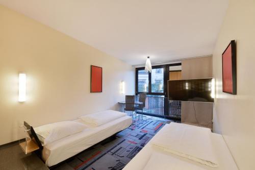 Schlafzimmer mit einem Bett, einem Schreibtisch und einem TV in der Unterkunft Hotel Wiehberg in Hannover