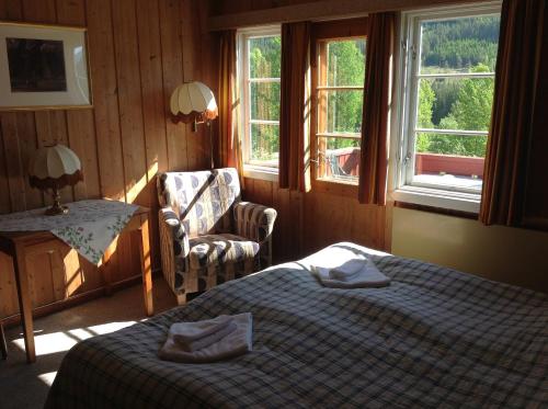 a bedroom with a bed and a chair and windows at Smedsgården Hotel in Nesbyen