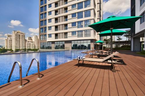 a deck with a table and umbrella next to a pool at Oakwood Residence Saigon in Ho Chi Minh City