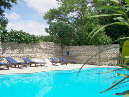 een zwembad met ligstoelen naast een bakstenen muur bij Château de l'Abbaye - Teritoria in Moreilles