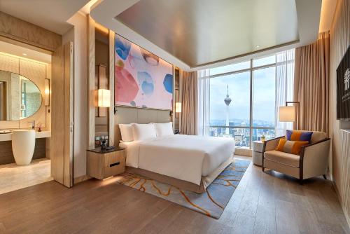 a bedroom with a bed and a chair and a large window at Banyan Tree Kuala Lumpur in Kuala Lumpur