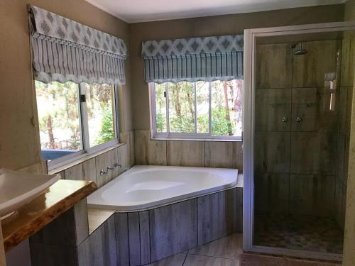 een badkamer met een groot bad en 2 ramen bij Meadow Lane Country Cottages in Underberg