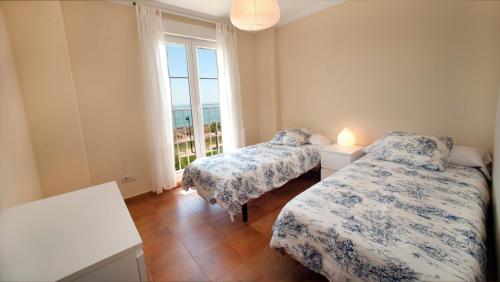 two beds in a room with a window at Leo Rentals in Isla Canela