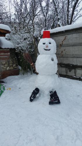 a snowman with a red hat sitting in the snow at Csaki Vendeghaz in Sovata