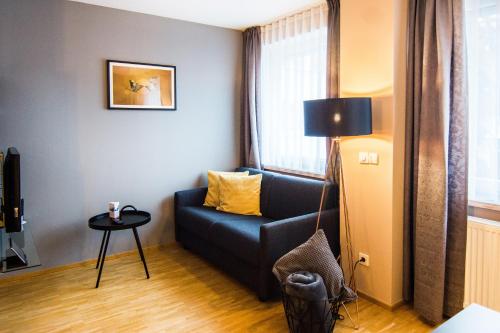 a living room with a blue couch and a table at zeitwohnhaus SUITE-HOTEL & SERVICED APARTMENTS in Erlangen