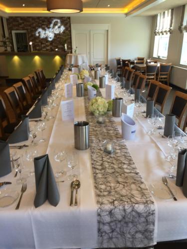 a long table in a banquet hall with wine glasses at Hotel Wuelfers Gasthaus in Groß Ippener