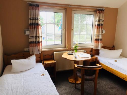 a room with two beds and a table and two windows at Hotel Wuelfers Gasthaus in Groß Ippener
