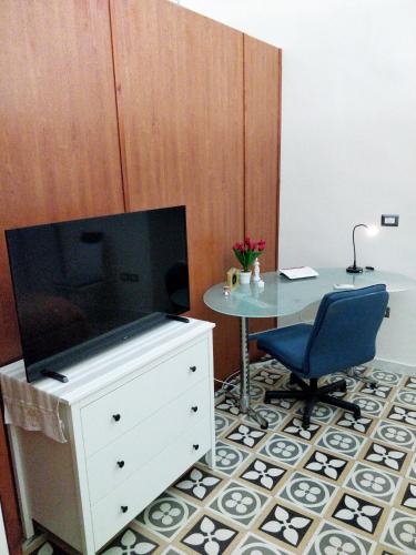 a dresser with a tv and a table with a chair at Appartamento Manfredi in Manfredonia