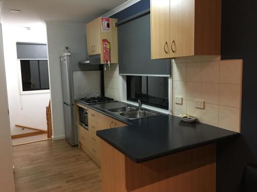 a kitchen with a black counter top and wooden cabinets at Villa by the Lake in Lakes Entrance