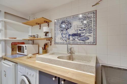 une cuisine avec un évier et un micro-ondes dans l'établissement 3 people - Place des Vosges Paris by Weekome, à Paris