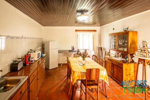 a kitchen with a table and a dining room at Hospedaria casa D'Avo in Praia da Vitória