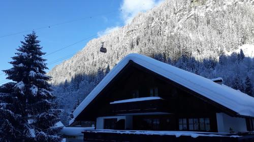 a ski lodge with a snow covered roof and a ski lift at Pension Backstuba in Partenen