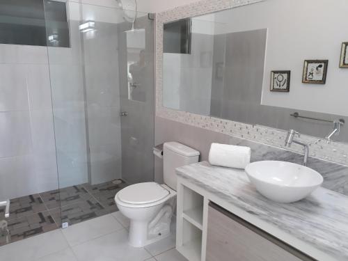 a white bathroom with a sink and a toilet at Fazenda Fiore Resort in Paripueira