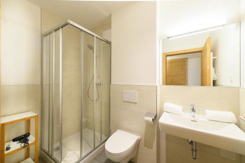 a bathroom with a shower and a toilet and a sink at Wander- und Familienhotel Erika in Wagrain