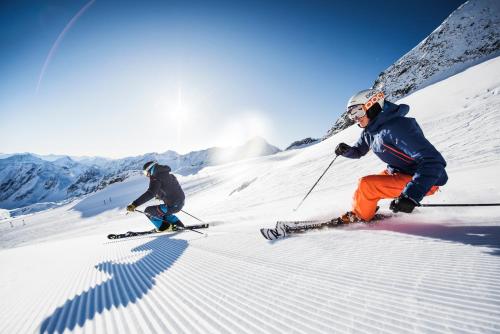 two people are skiing down a snow covered slope at Familien- & Vitalhotel Auenhof in Fulpmes