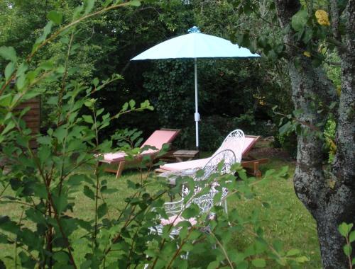 a couple of chairs and an umbrella in a yard at Château de l'Abbaye - Teritoria in Moreilles