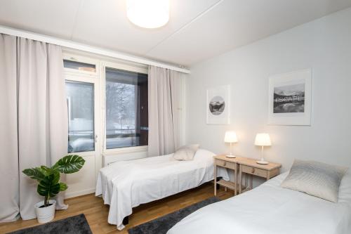 een slaapkamer met 2 bedden en een raam bij Kotimaailma Apartments Vaasa in Vaasa