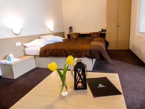 ELITE HOTEL Nová Dubnica في Nová Dubnica: غرفة في الفندق بها سرير وطاولة بها زهور