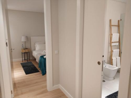 a white room with a bed and a bathroom at Rafaelo's Apartment in Caldas da Rainha