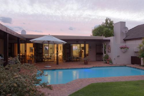 a house with a swimming pool and an umbrella at Majorca House in Somerset West