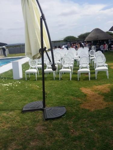an umbrella stand in front of a group of white chairs at Vido Lodge and Conference Centre in Polokwane