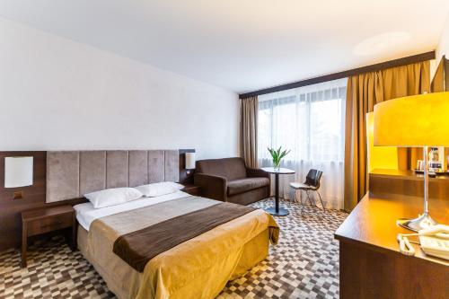 a hotel room with a bed and a chair at Hotel Solny in Kołobrzeg