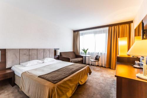 a hotel room with a large bed and a chair at Hotel Solny in Kołobrzeg