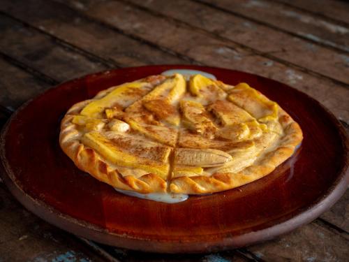 a pie on a red plate on a wooden table at Pousada da Rosa in Ilhabela