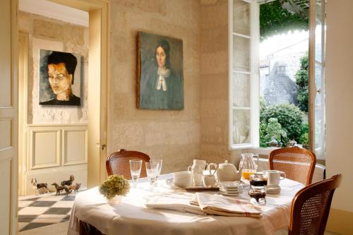 une salle à manger avec une table et un chiffon de table blanc dans l'établissement La Porte Rouge - The Red Door Inn, à Saintes
