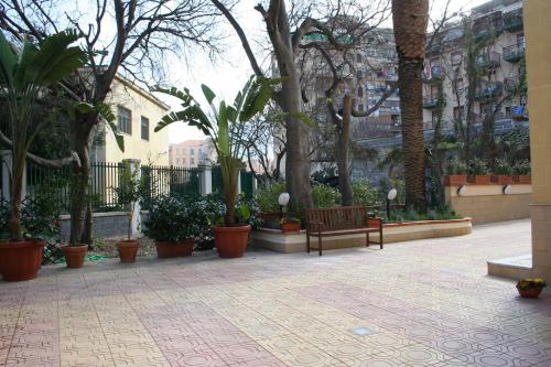 a courtyard with benches and trees and buildings at Hotel d'Orleans in Palermo