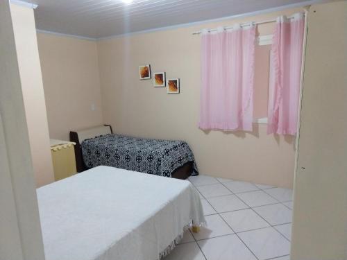 a bedroom with two beds and a window with pink curtains at Casa para verão em Balneário Gaivota in Balneário Gaivotas