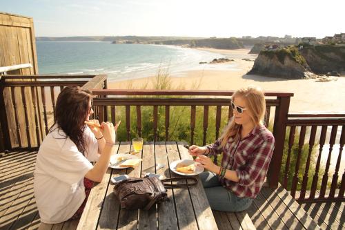 ニューキーにあるSt Christopher's Inn Newquayの二人の女性がテーブルに座ってビーチで食事をしている
